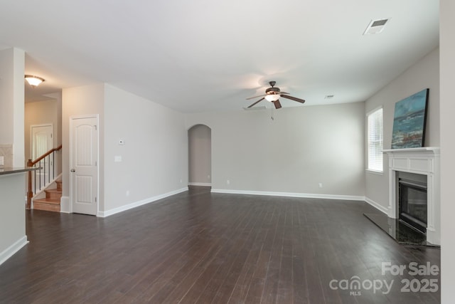 11922 Kimberfield Rd, Matthews, NC 28105 - unfurnished living room with a ceiling fan, a glass covered fireplace, arched walkways, dark wood finished floors, and stairway