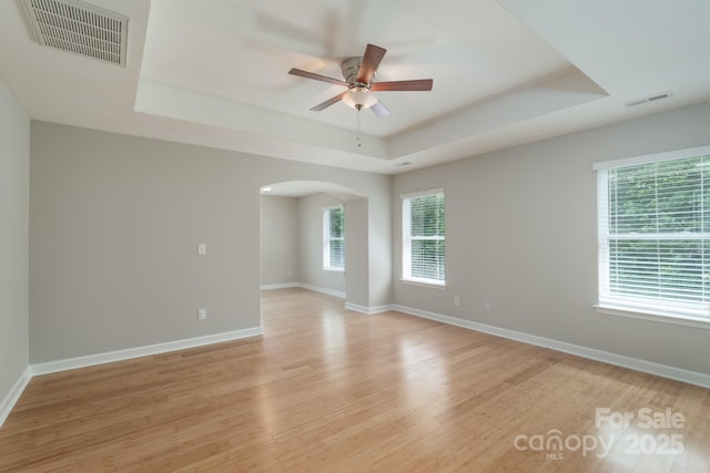11922 Kimberfield Rd, Matthews, NC 28105 - unfurnished room with a tray ceiling, arched walkways, a ceiling fan, and light wood-type flooring