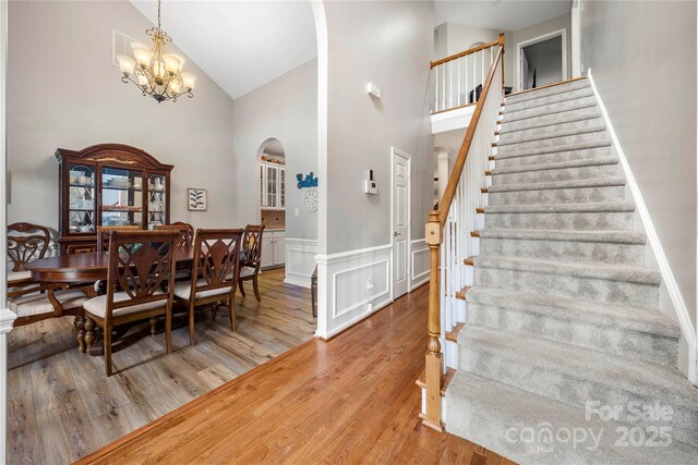 162 Castles Gate Dr, Mooresville, NC 28117 - dining room featuring arched walkways, high vaulted ceiling, stairs, wood finished floors, and a chandelier