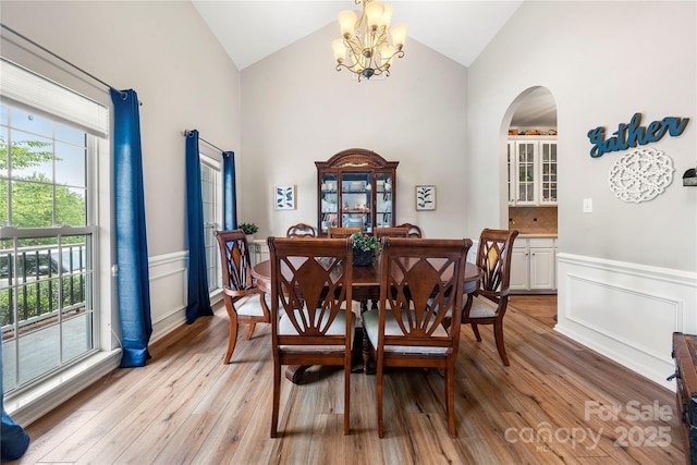 162 Castles Gate Dr, Mooresville, NC 28117 - dining room with a chandelier, wainscoting, arched walkways, light wood-style flooring, and a decorative wall