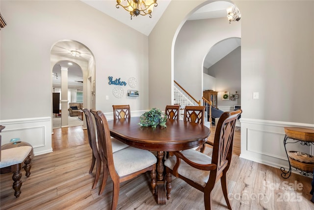 162 Castles Gate Dr, Mooresville, NC 28117 - dining space featuring stairs, light wood-type flooring, arched walkways, a wainscoted wall, and high vaulted ceiling