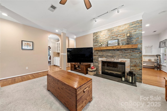 162 Castles Gate Dr, Mooresville, NC 28117 - living room featuring arched walkways, a stone fireplace, ceiling fan, crown molding, and wood finished floors