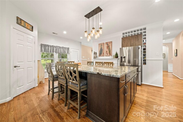 162 Castles Gate Dr, Mooresville, NC 28117 - kitchen with stainless steel fridge, arched walkways, a kitchen island, light wood finished floors, and a kitchen bar