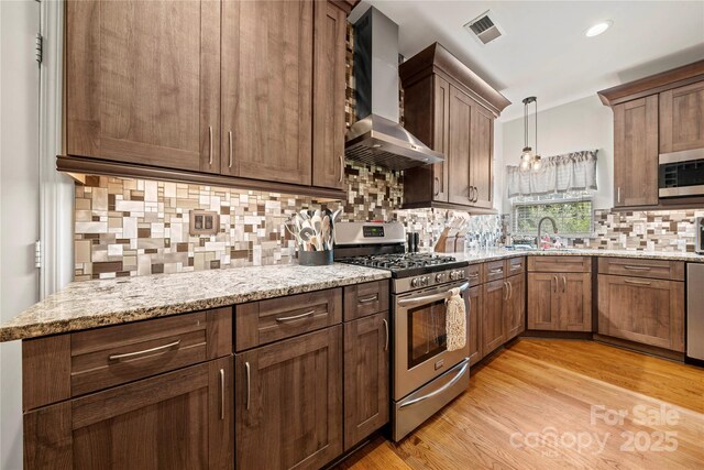 162 Castles Gate Dr, Mooresville, NC 28117 - kitchen with stainless steel appliances, wall chimney exhaust hood, tasteful backsplash, light stone countertops, and light wood-type flooring