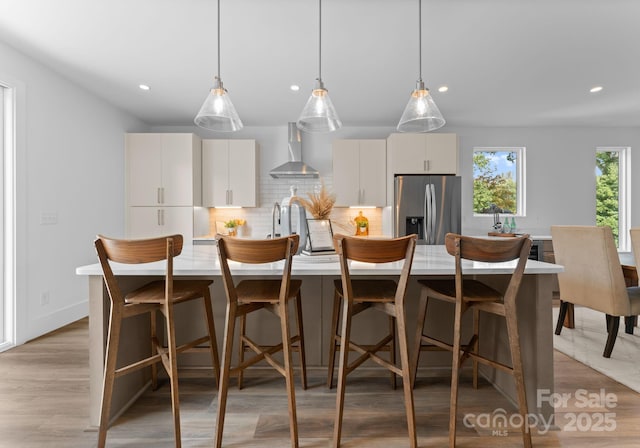 209 Keswick Ave, Charlotte, NC 28206 - kitchen featuring stainless steel fridge with ice dispenser, wall chimney range hood, tasteful backsplash, recessed lighting, and light countertops