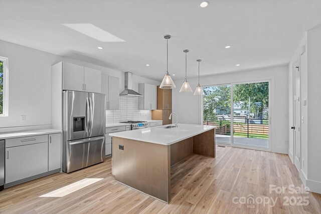209 Keswick Ave, Charlotte, NC 28206 - kitchen with appliances with stainless steel finishes, wall chimney range hood, a skylight, light countertops, and backsplash
