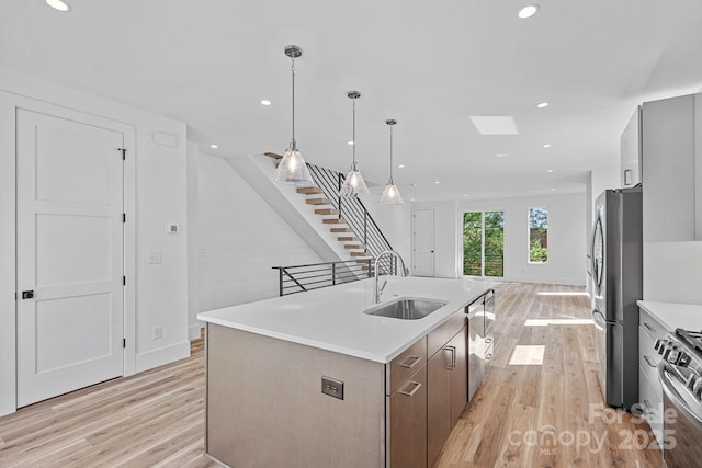 209 Keswick Ave, Charlotte, NC 28206 - kitchen featuring appliances with stainless steel finishes, light wood-type flooring, light countertops, recessed lighting, and a center island with sink