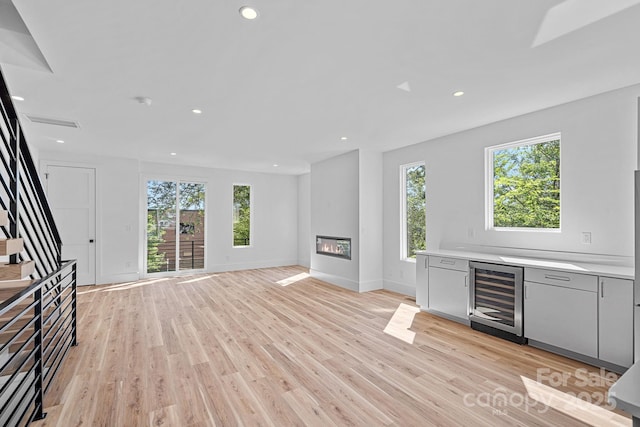 209 Keswick Ave, Charlotte, NC 28206 - unfurnished living room featuring beverage cooler, plenty of natural light, a glass covered fireplace, stairs, and recessed lighting