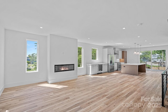 209 Keswick Ave, Charlotte, NC 28206 - unfurnished living room featuring beverage cooler, a glass covered fireplace, light wood-style flooring, and recessed lighting