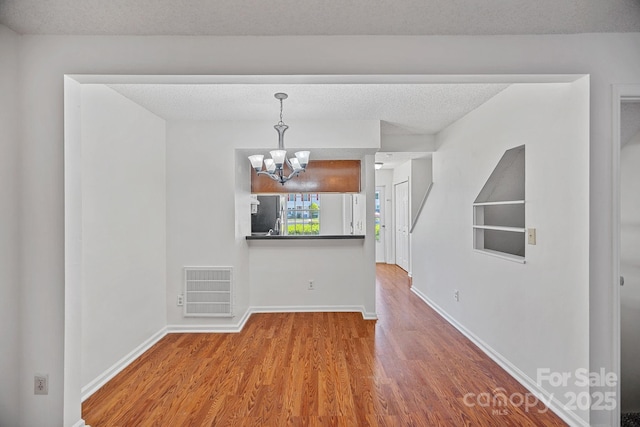 218 Water Oak Dr, Pineville, NC 28134 - unfurnished dining area with a chandelier, wood finished floors, and a textured ceiling