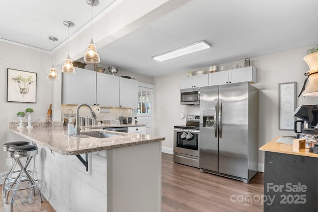 120 Hilltop St, Connelly Springs, NC 28612 - kitchen featuring stainless steel appliances, a peninsula, light stone countertops, a kitchen bar, and wood finished floors