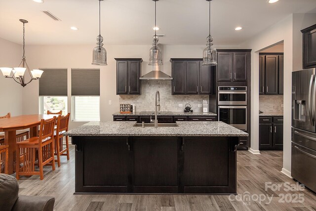 171 Old Harbor Dr, Mount Gilead, NC 27306 - kitchen featuring appliances with stainless steel finishes, a chandelier, light wood finished floors, decorative backsplash, and light stone counters