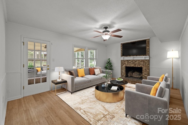 906 Wishing Well Ln, Charlotte, NC 28270 - living area featuring wood finished floors, a ceiling fan, a brick fireplace, a textured ceiling, and a wainscoted wall