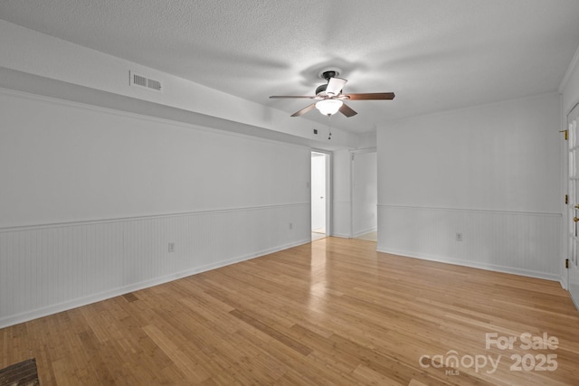 906 Wishing Well Ln, Charlotte, NC 28270 - spare room with ceiling fan, light wood finished floors, a wainscoted wall, and a textured ceiling