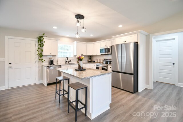 339 Brown Rd, China Grove, NC 28023 - kitchen featuring appliances with stainless steel finishes, a breakfast bar area, light wood-style floors, white cabinetry, and recessed lighting