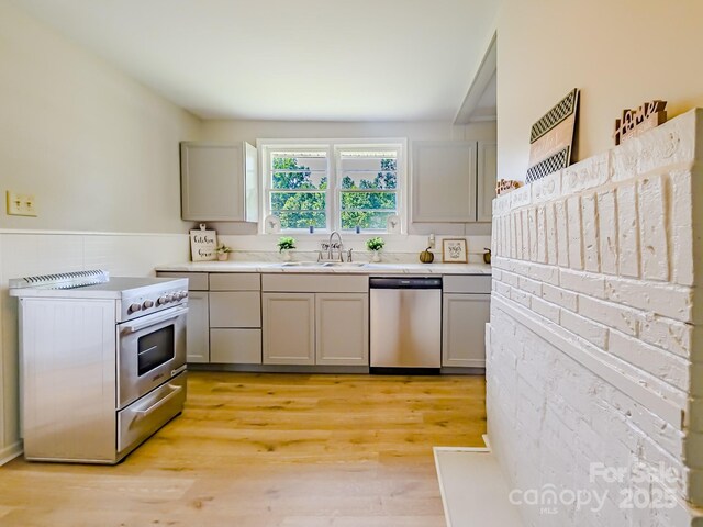 106 Cedar St, Spindale, NC 28160 - kitchen with appliances with stainless steel finishes, gray cabinets, light countertops, a sink, and light wood-style floors