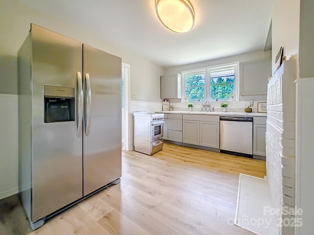 106 Cedar St, Spindale, NC 28160 - kitchen with stainless steel appliances, light wood finished floors, light countertops, a sink, and wainscoting