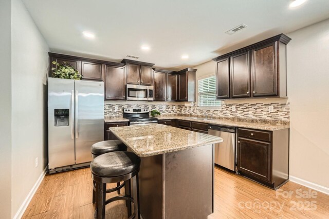 4151 Granite St, Midland, NC 28107 - kitchen featuring appliances with stainless steel finishes, dark brown cabinetry, light wood-style flooring, a center island, and backsplash