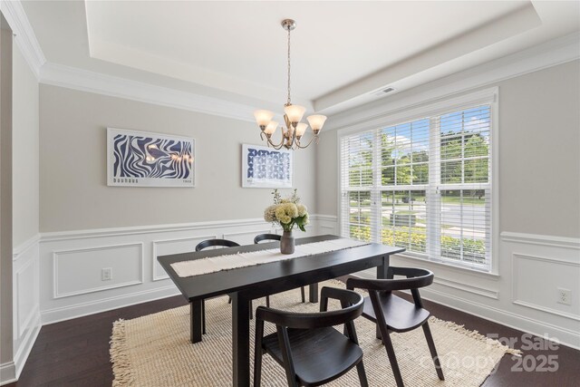 1830 Alden Oaks Ln, Charlotte, NC 28270 - dining room featuring a tray ceiling, a chandelier, a wainscoted wall, dark wood-style flooring, and a decorative wall
