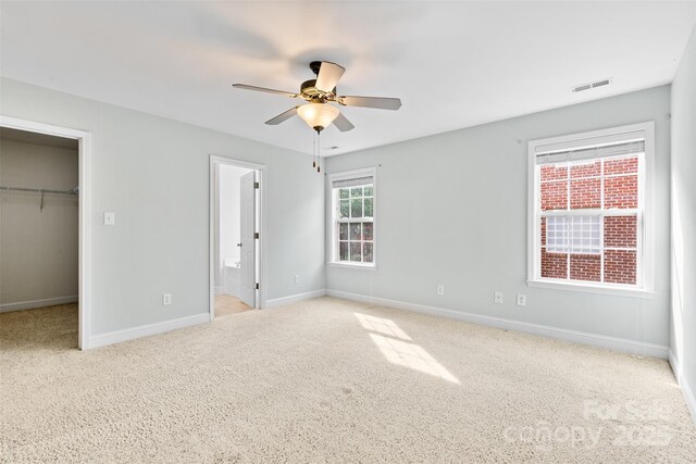 5707 Sustar Dr, Monroe, NC 28110 - unfurnished bedroom with a walk in closet, carpet flooring, a closet, connected bathroom, and a ceiling fan
