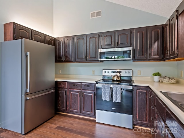 848 Eagles Ridge Rd, Sylva, NC 28779 - kitchen with appliances with stainless steel finishes, lofted ceiling, light countertops, dark wood-style flooring, and dark brown cabinetry