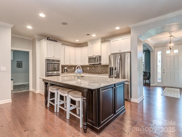 314 Candella Dr, Matthews, NC 28104 - kitchen featuring appliances with stainless steel finishes, arched walkways, baseboards, white cabinets, and recessed lighting
