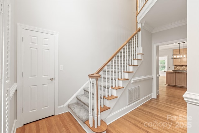 7301 Leharne Dr, Charlotte, NC 28270 - staircase with wood finished floors, ornamental molding, and a chandelier