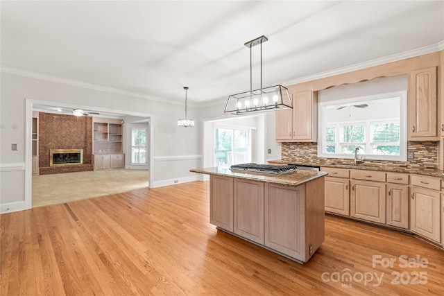 7301 Leharne Dr, Charlotte, NC 28270 - kitchen with light brown cabinets, light wood-style flooring, dark stone counters, a kitchen island, and stainless steel gas stovetop