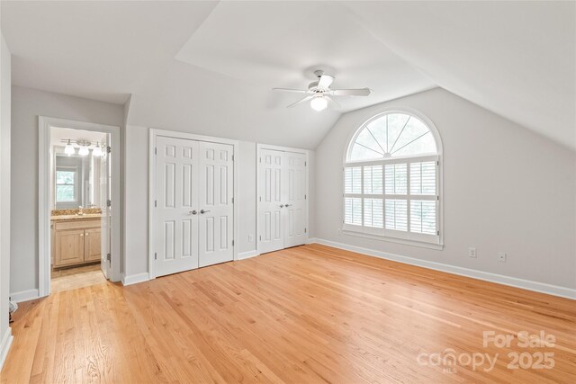 7301 Leharne Dr, Charlotte, NC 28270 - unfurnished bedroom featuring two closets, light wood-type flooring, vaulted ceiling, ensuite bath, and a ceiling fan