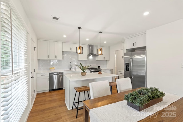 922 Maurice St, Monroe, NC 28112 - kitchen featuring appliances with stainless steel finishes, wall chimney range hood, a center island, tasteful backsplash, and light countertops