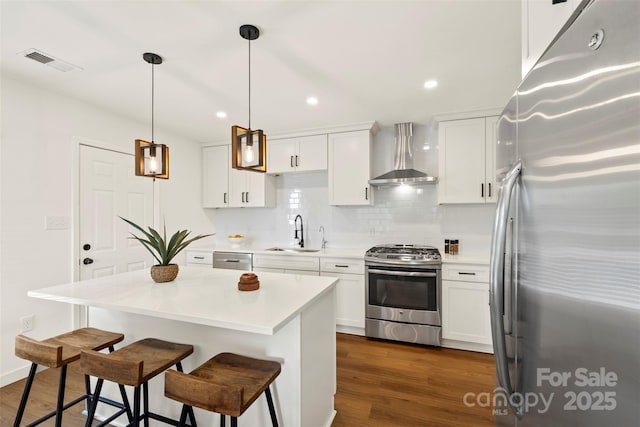 922 Maurice St, Monroe, NC 28112 - kitchen with stainless steel appliances, wall chimney exhaust hood, a kitchen breakfast bar, decorative backsplash, and white cabinetry