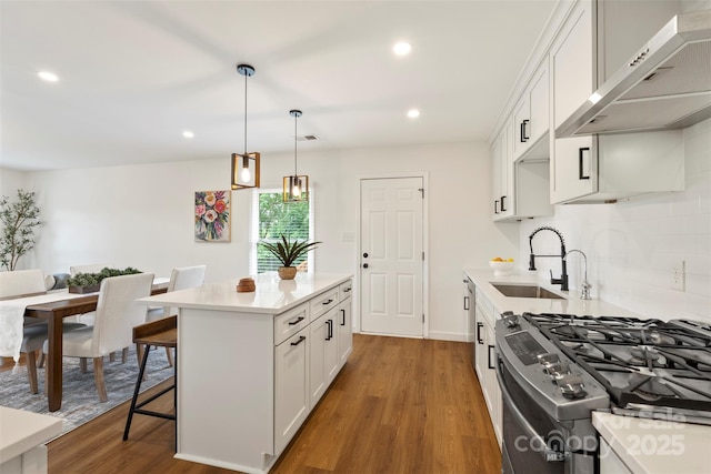 922 Maurice St, Monroe, NC 28112 - kitchen featuring ventilation hood, stainless steel gas range oven, wood finished floors, a kitchen bar, and white cabinets