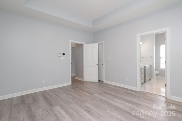 12321 Aquitaine St, Charlotte, NC 28277 - unfurnished bedroom with light wood-type flooring, ensuite bath, and a raised ceiling