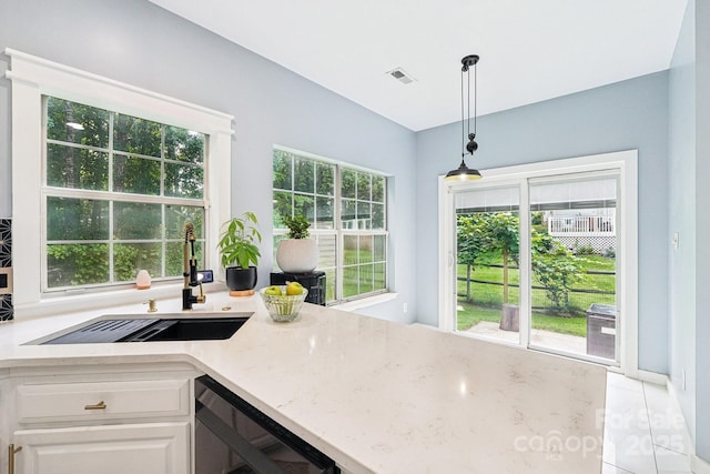 8618 Sam Dee Rd, Charlotte, NC 28215 - kitchen with stainless steel dishwasher, light stone countertops, white cabinets, hanging light fixtures, and light tile patterned flooring