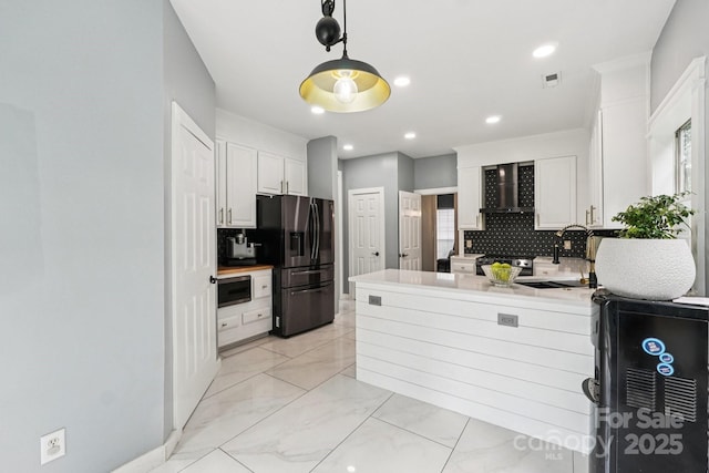 8618 Sam Dee Rd, Charlotte, NC 28215 - kitchen featuring appliances with stainless steel finishes, wall chimney range hood, backsplash, light countertops, and a peninsula