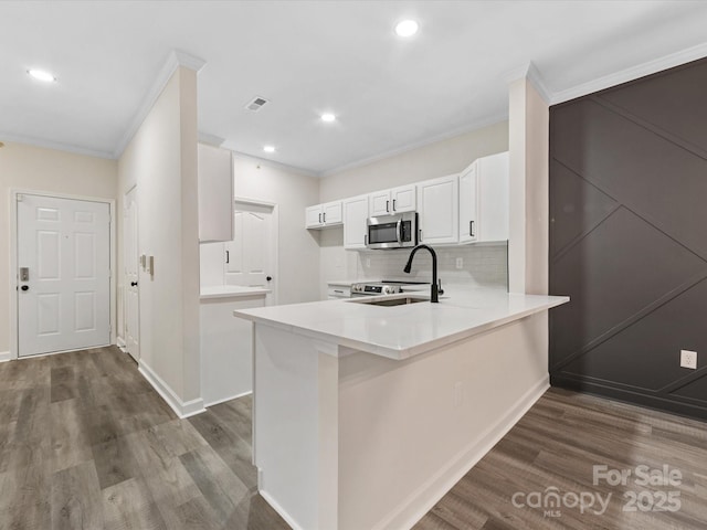 17136 Red Feather Dr, Charlotte, NC 28277 - kitchen with stainless steel microwave, crown molding, dark wood finished floors, a peninsula, and white cabinetry
