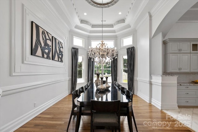 7068 Denison Rd, Summerfield, NC 27358 - dining space with a chandelier, crown molding, light wood-style flooring, arched walkways, and a high ceiling