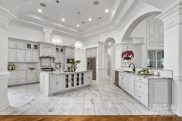 7068 Denison Rd, Summerfield, NC 27358 - kitchen featuring stainless steel appliances, gray cabinets, arched walkways, a tray ceiling, and a towering ceiling