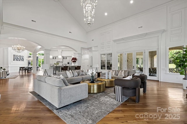 7068 Denison Rd, Summerfield, NC 27358 - living area featuring a chandelier, arched walkways, decorative columns, high vaulted ceiling, and wood finished floors