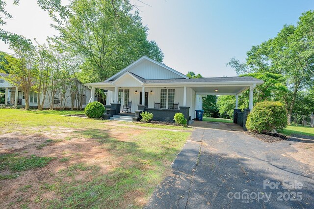 506 E Main St, Forest City, NC 28043 - view of front facade with asphalt driveway, a carport, a porch, board and batten siding, and a front yard