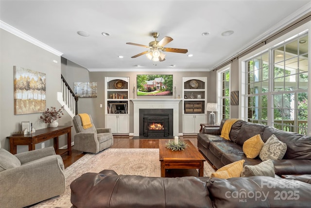 6006 Casswell Cir, Matthews, NC 28104 - living area featuring ornamental molding, wood finished floors, ceiling fan, stairway, and a fireplace with flush hearth