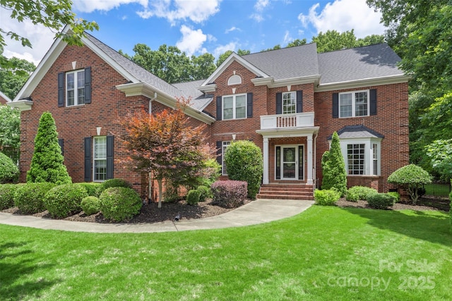 6006 Casswell Cir, Matthews, NC 28104 - colonial-style house featuring brick siding, a front yard, a shingled roof, and a balcony
