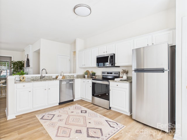9030 Gander Dr, Charlotte, NC 28277 - kitchen with stainless steel appliances, a peninsula, white cabinets, light wood-style floors, and light stone countertops