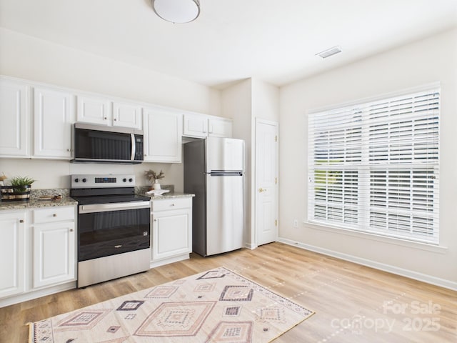 9030 Gander Dr, Charlotte, NC 28277 - kitchen with appliances with stainless steel finishes, white cabinets, light wood finished floors, and light stone counters