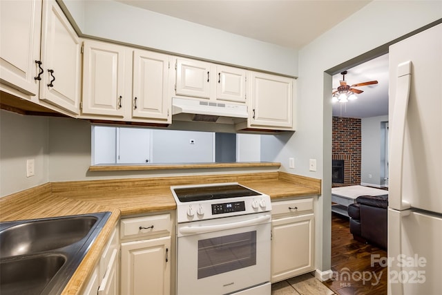 1606 Sharon Rd W Unit 40, Charlotte, NC 28210 - kitchen with white appliances, a ceiling fan, under cabinet range hood, white cabinetry, and a brick fireplace