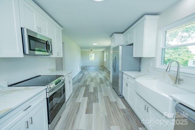1696 Race Path Church Rd, Mooresboro, NC 28114 - kitchen featuring appliances with stainless steel finishes, white cabinets, light wood finished floors, and light stone counters