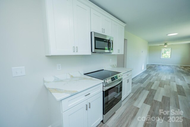 1696 Race Path Church Rd, Mooresboro, NC 28114 - kitchen with appliances with stainless steel finishes, white cabinets, light wood-type flooring, a ceiling fan, and light stone counters