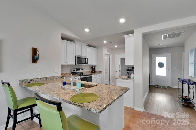 410 Apex Cir, Shelby, NC 28152 - kitchen featuring stainless steel appliances, light wood-style flooring, white cabinetry, a breakfast bar, and light stone counters
