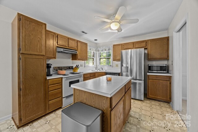 212 Foxfield Ln, Matthews, NC 28105 - kitchen featuring stainless steel appliances, light floors, under cabinet range hood, and brown cabinetry