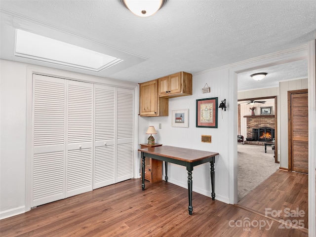 185 Indian Springs Rd, Clyde, NC 28721 - kitchen featuring wood finished floors, light brown cabinets, a textured ceiling, and a fireplace
